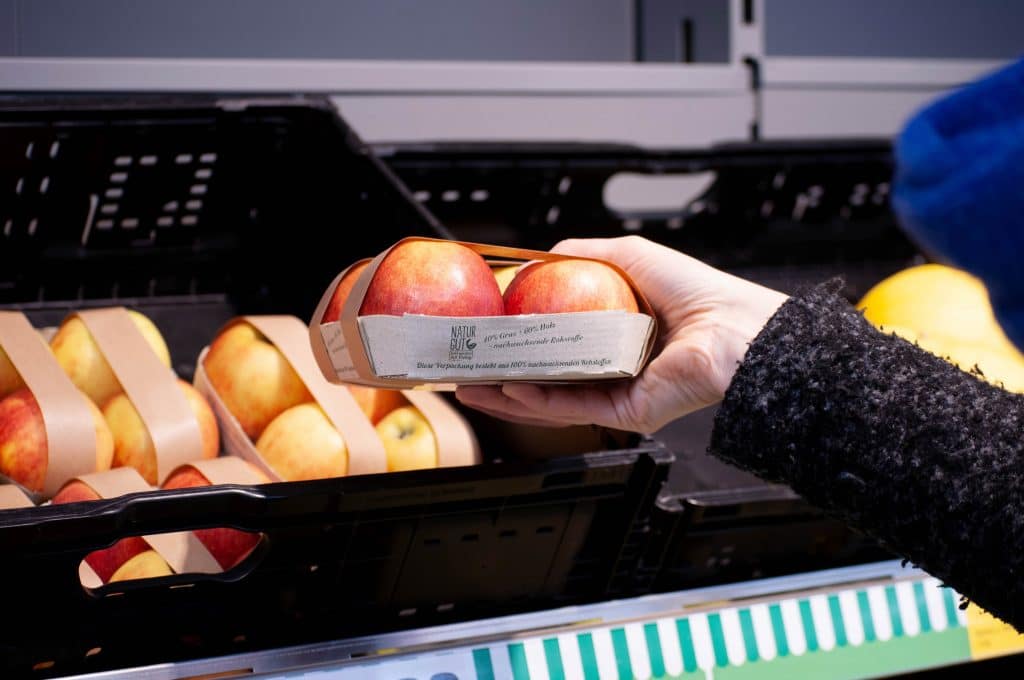 Frau nimmt eine Packung mit Äpfel aus dem Regal