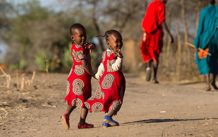 Zwei Mädchen halten Händchen und winken