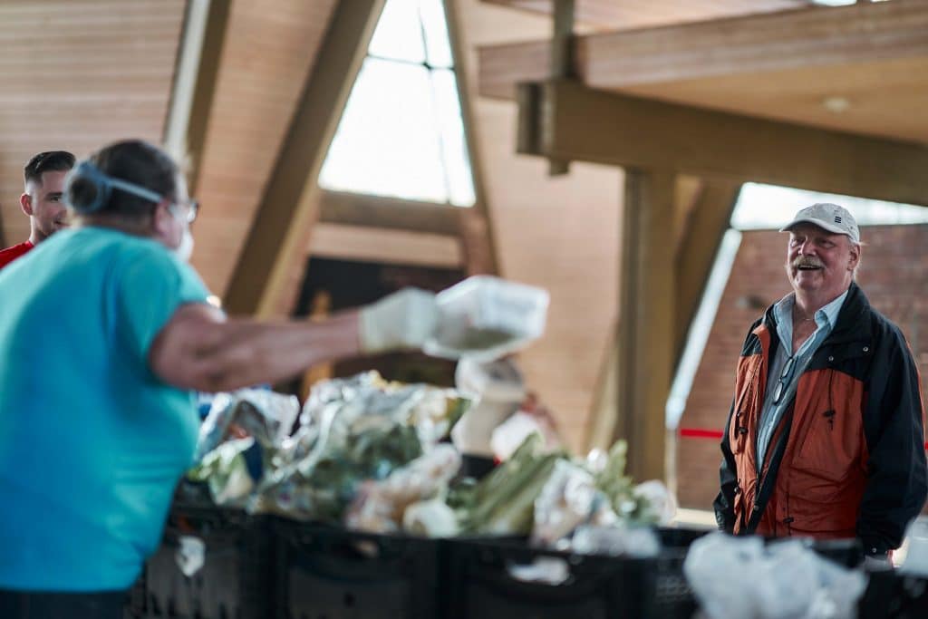 Drei Männer unterhalten sich und sortieren Nahrungsmittel
