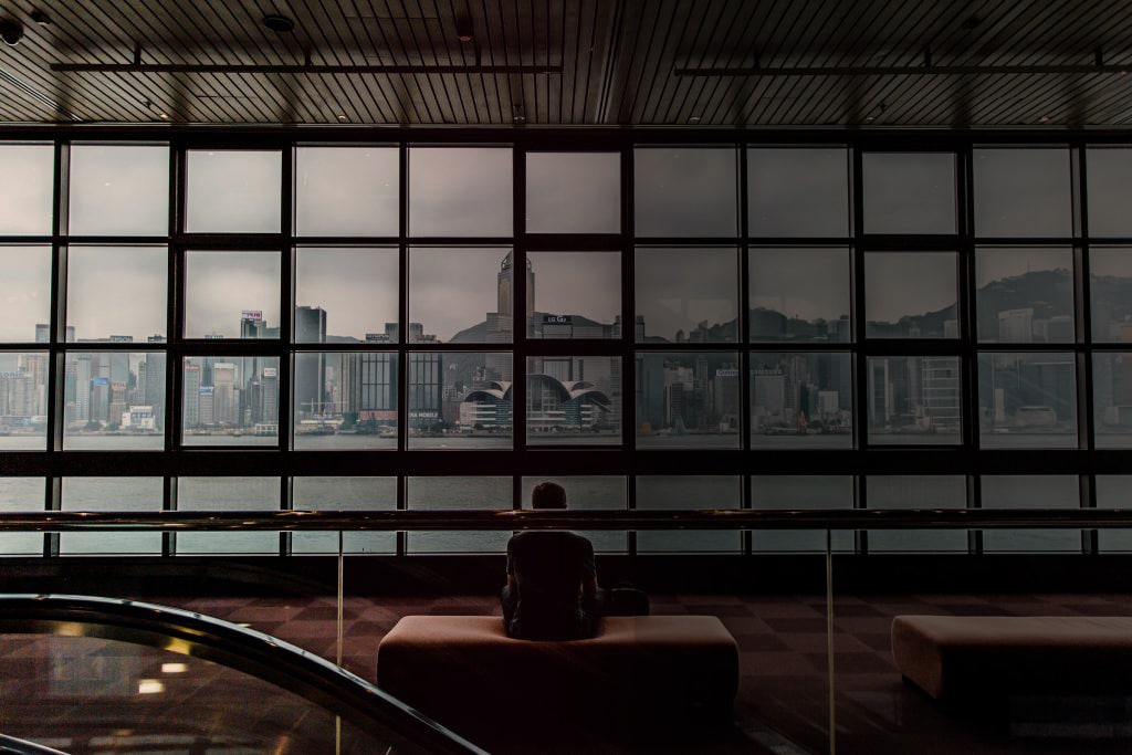 Mann sitzt vor einer Fensterfront