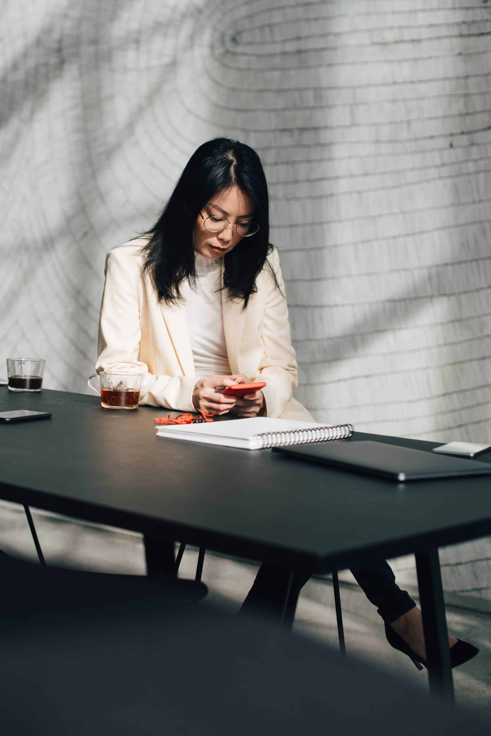 YOUNG WOMAN SITTING ON TABLE IN OFFICE