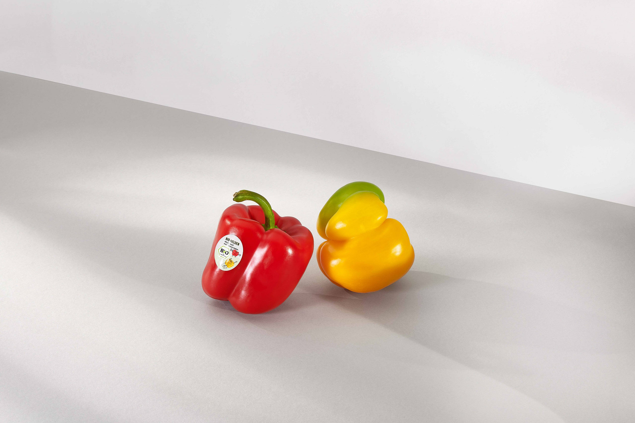 Zwei Paprikas eine rote und eine gelbe vor grauem Hintergrund