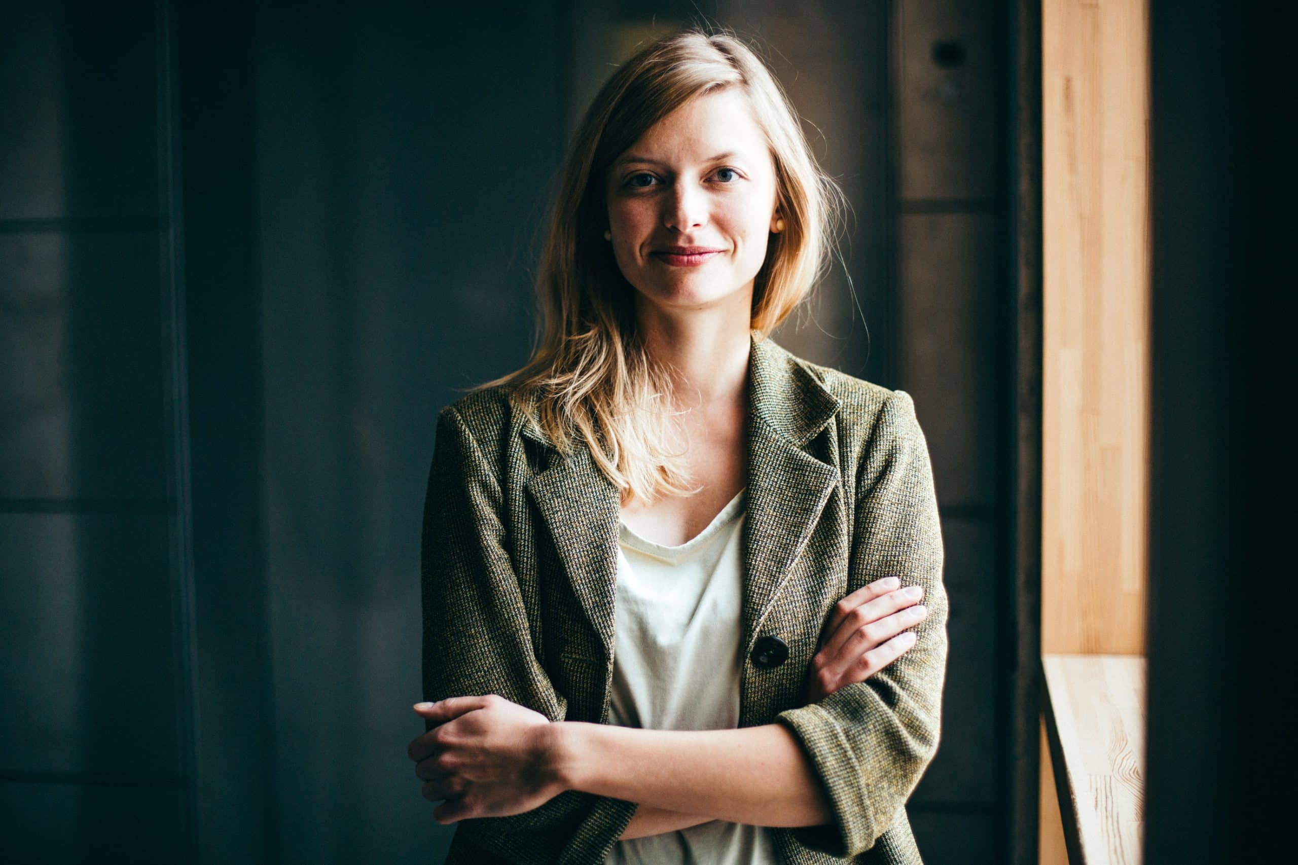 Porträt einer lächelnden Frau mit verschränkten Armen als Symbolbild für Transparenz