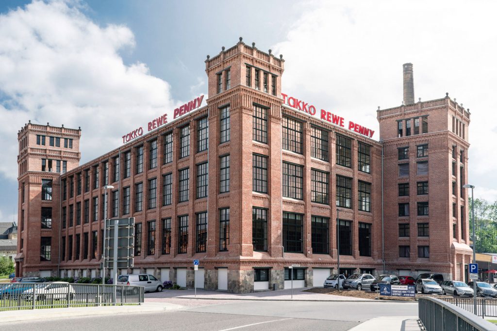 Ein denkmalgeschützes Gebäude, in dem ein REWE, ein PENNY und ein Takko Markt angesiedelt sind