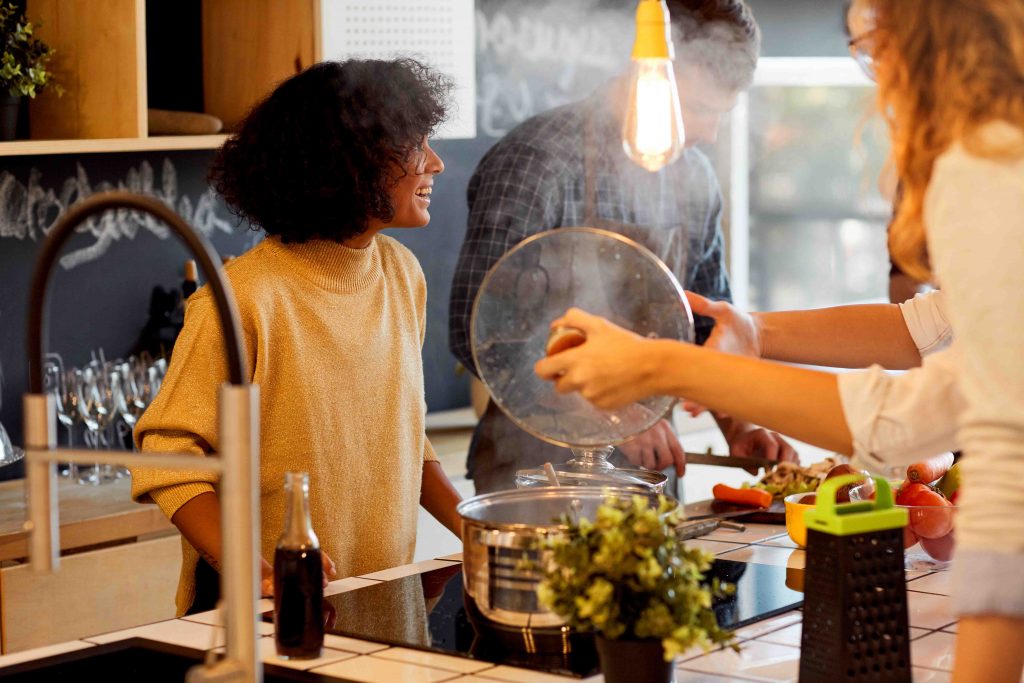 Eine Gruppe von Freunden steht in der Küche und kocht zusammen