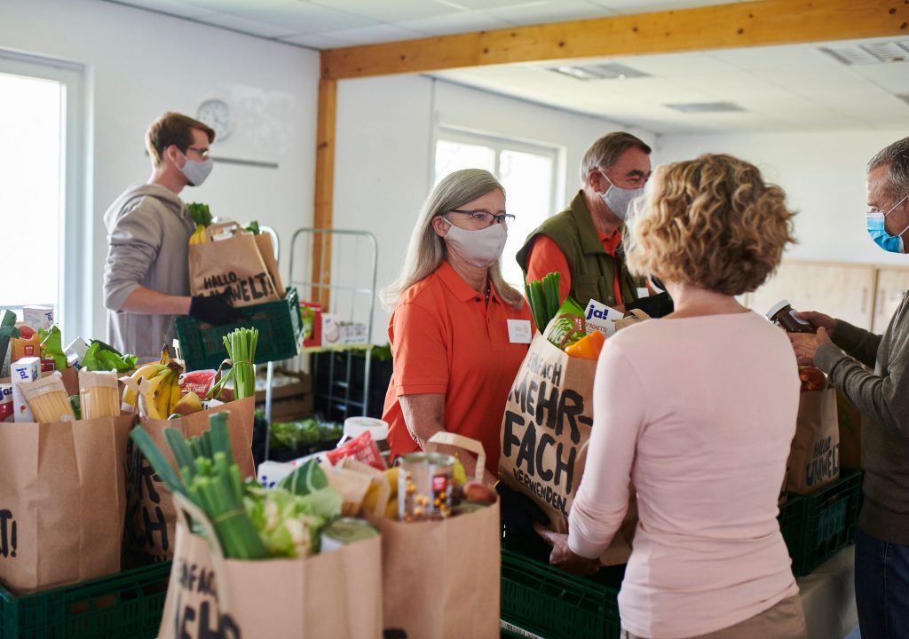 Mitarbeiterin der Tafel verteilt REWE Tafeltüten