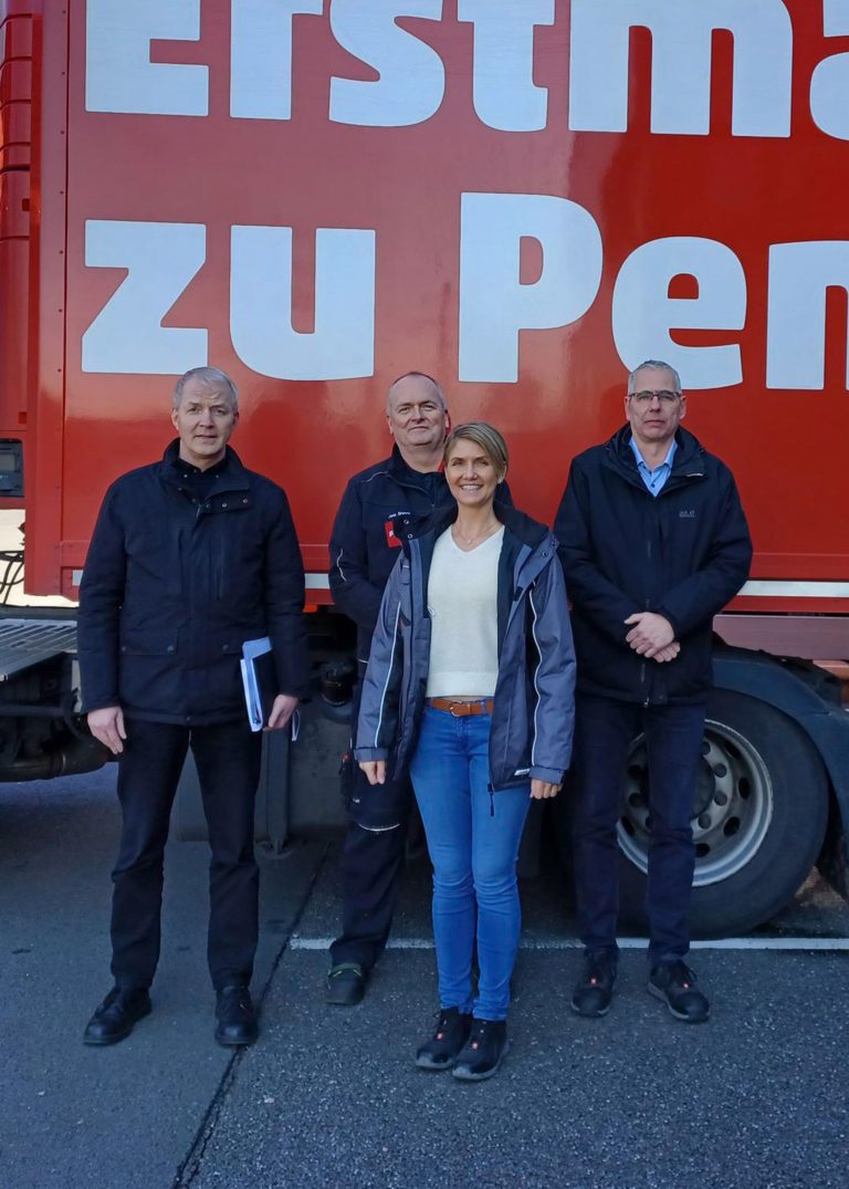 Verena Hammer mit mehreren Mitarbeitenden vor einem PENNY Fahrzeug.