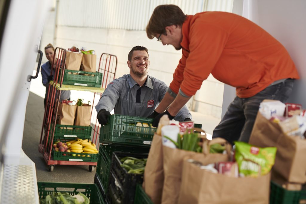 REWE- und Tafelmitarbeitende packen gemeinsam Tafeltüten
