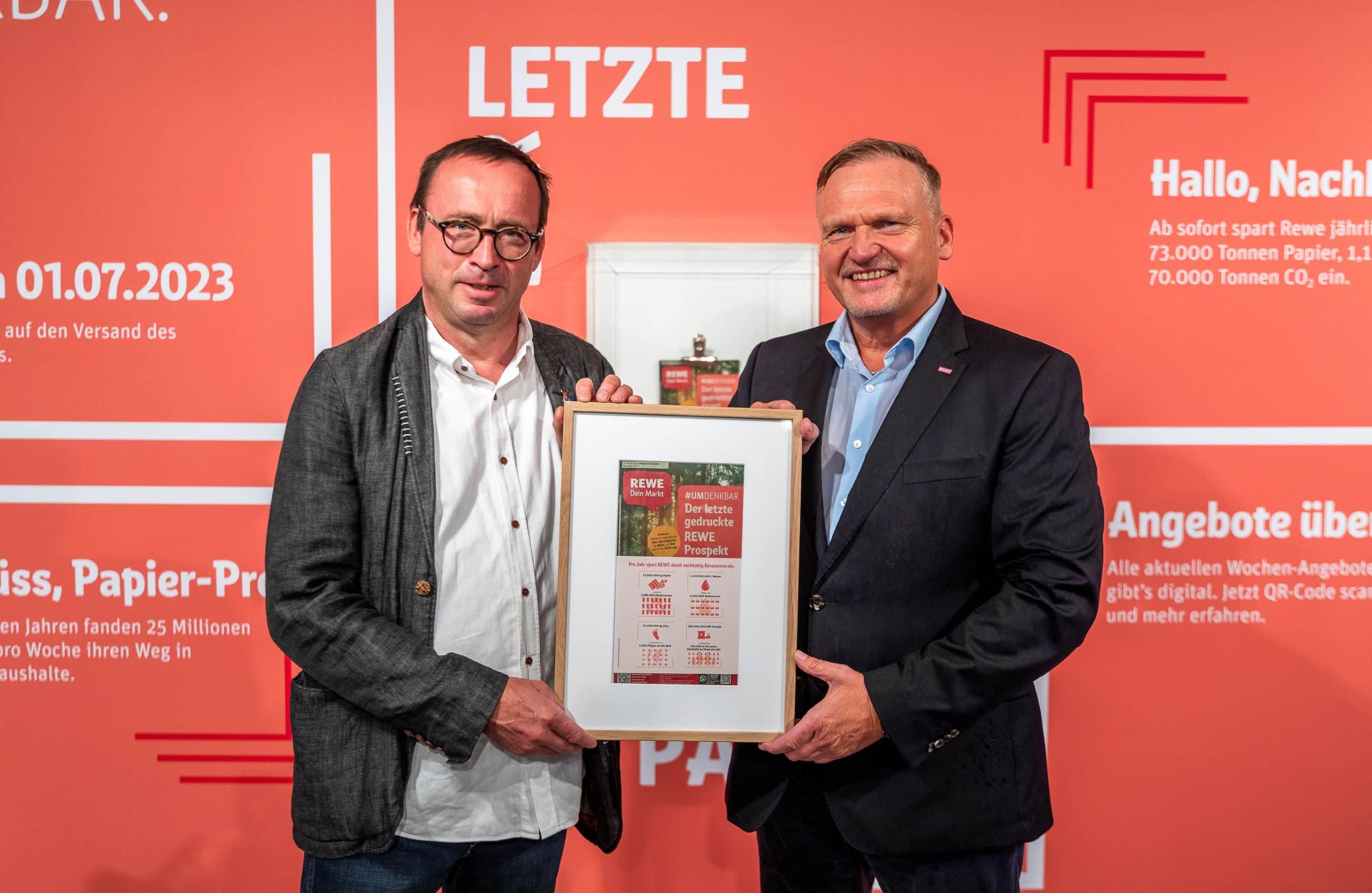 Links Leif Miller, Bundesgeschäftsführer des NABU, und Peter Maly, Vorstand der REWE Group, rechts mit dem letzten Papierprospekt.