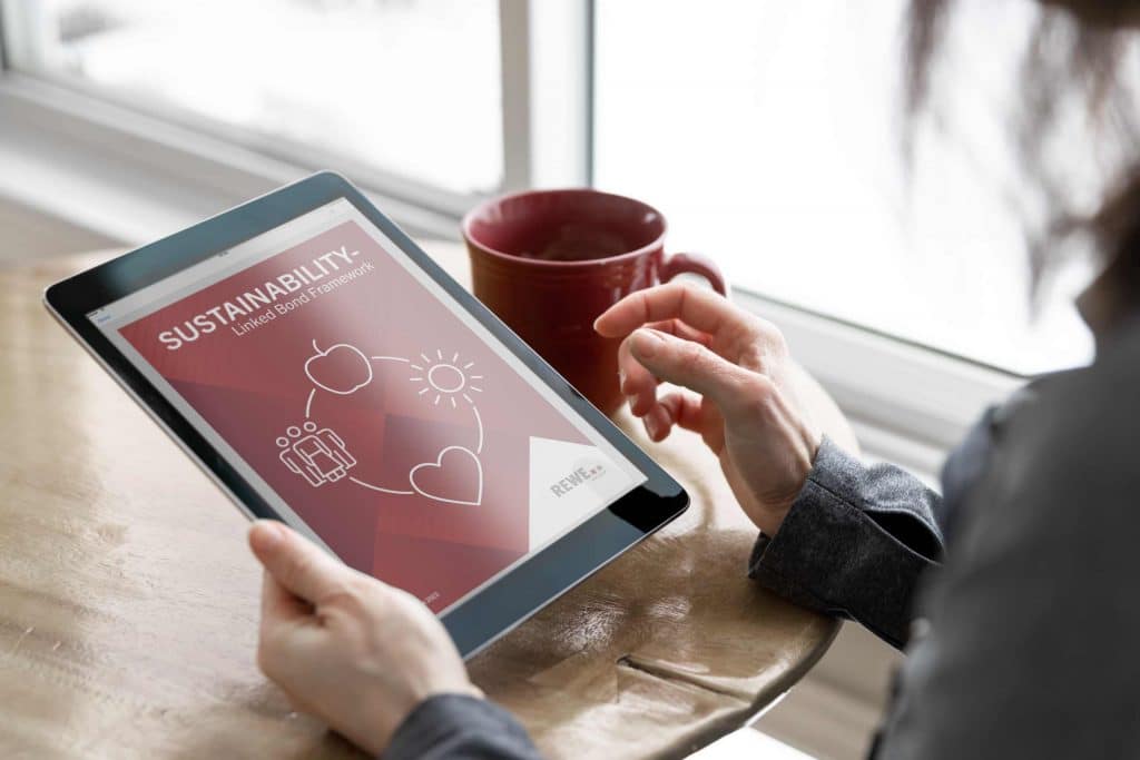 Person mit Tablet die eine Broschüre zum Thema Sustainability-Linked Bond Framework geöffnet hat.