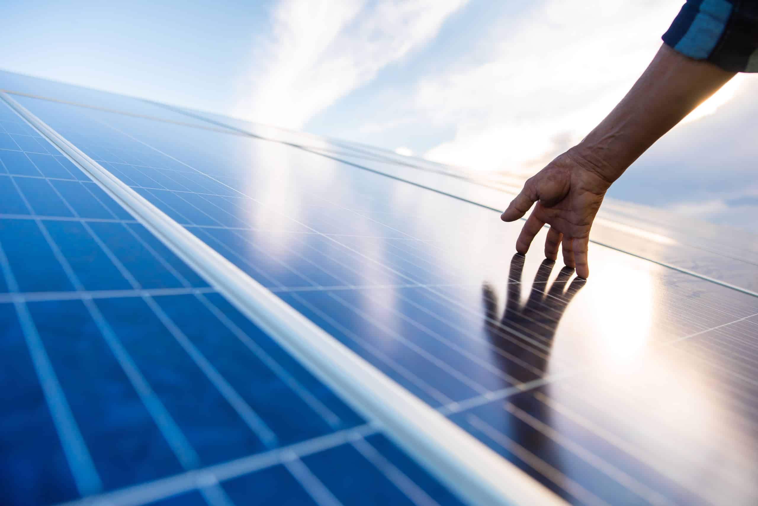 Hand auf einem Modul eine Photovoltaik Anlage