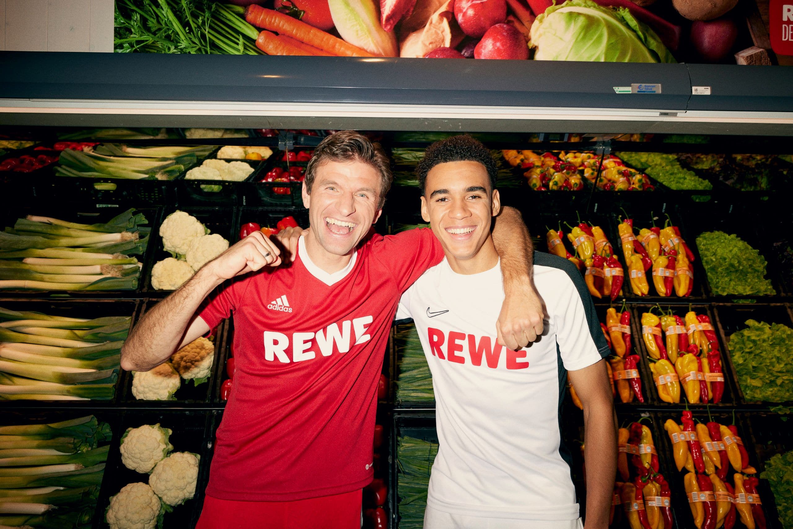 Bild von Thomas Müller und Jamal Musiala vor einem Gemüseregal